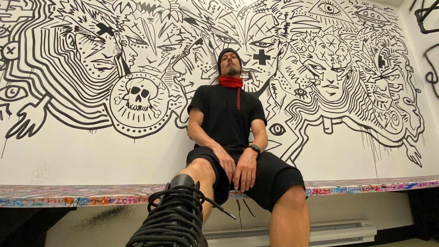 Jonathan Brunelle porte un t-shirt en laine et pose devant l'oeuvre permanente de Zilon dans le vertiaire du Musée des beaux-arts de Mont-Saint-Hilaire.