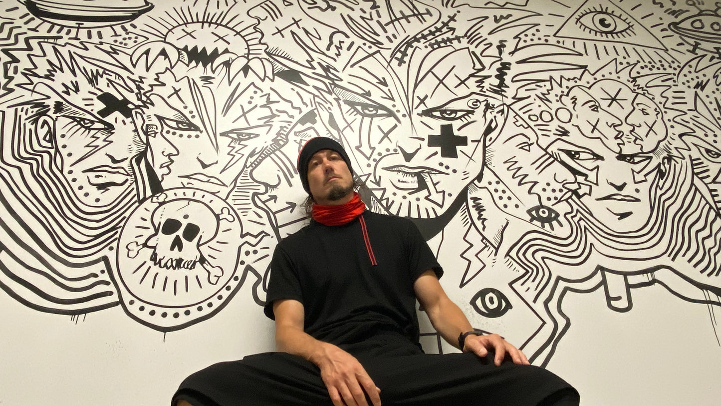 Jonathan Brunelle porte un cache cou rouge en laine devant l'oeuvre de Zilon dans le vestiaire du Musée des beaux-arts de Mont-Saint-Hilaire.