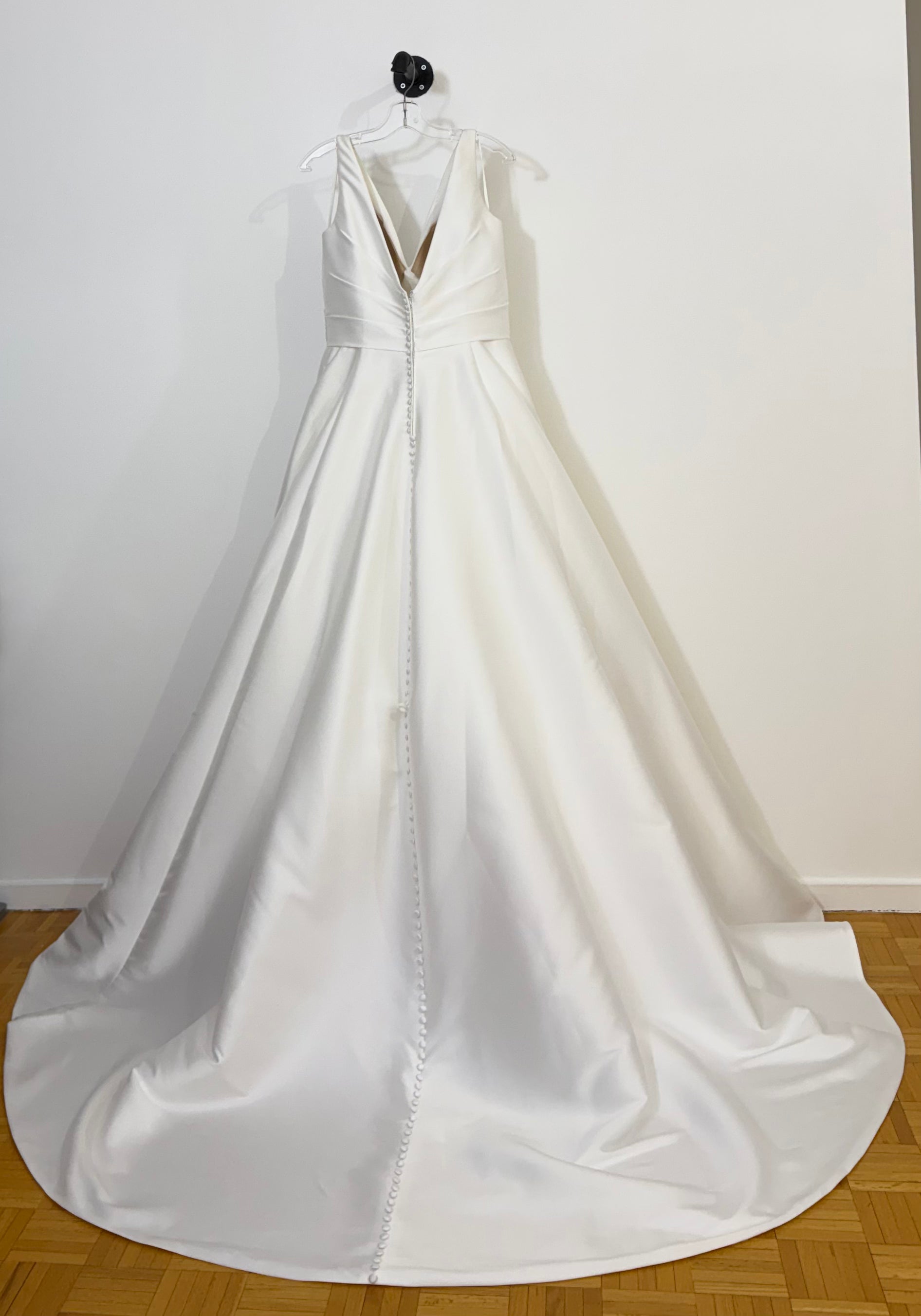 White wedding gown on a hanger against a white wall in Verdun, Montreal. ELZi Studio. 