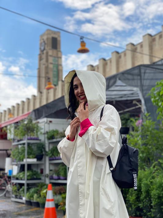 Sanaz wears an ELZI Waterproof White Raincoat in front of the atwater market. Sanaz porte un imperméable blanc ELZI devant le marché atwater.